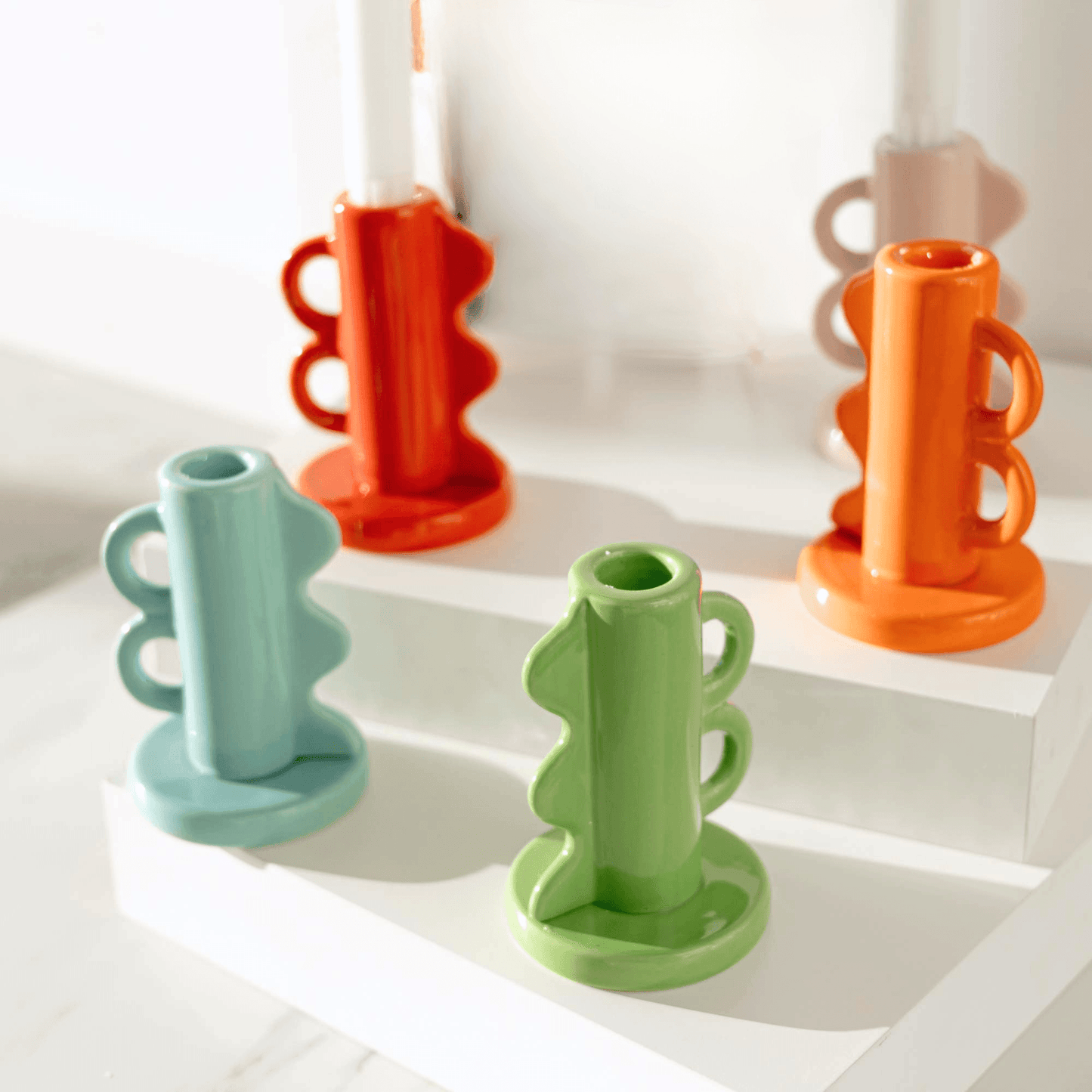 Colorful ceramic candle holders on a white surface