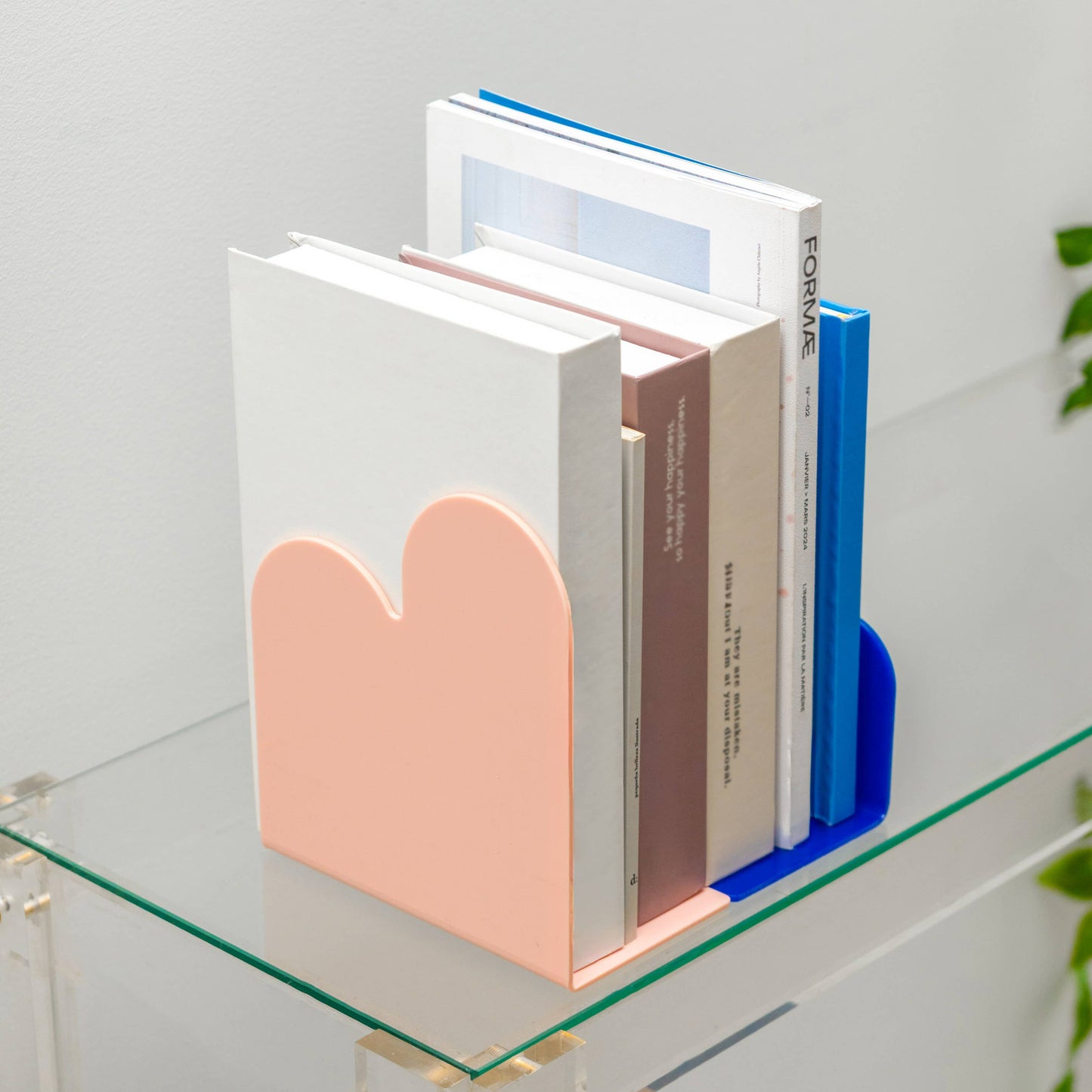 Colorful bookends holding books on a glass surface with a light gray background